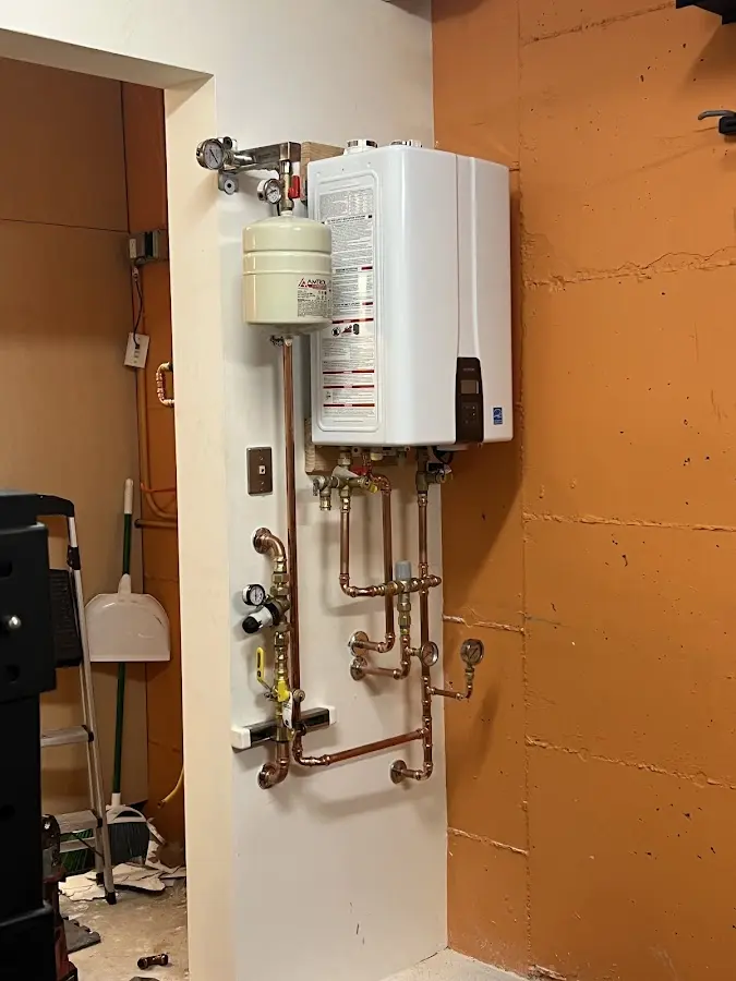 Plumbing technician inspecting water heater connections in Warrensburg